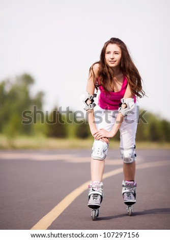 happy young brunette woman roller skating in the park