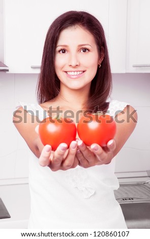 beautiful young woman with two tomatoes in the kitchen at home