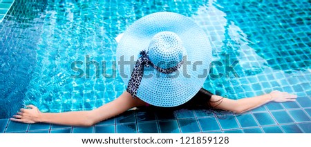 young woman wearing a blue hat sitting in the swimming pool