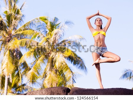 beautiful young woman practicing yoga outdoor at the tropical resort