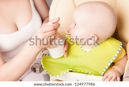 mother feeding her one year old daughter at home