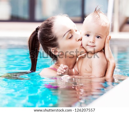 Beautiful Young Brunette Woman With Her One Year Old Baby Relaxing In The Swimming Pool