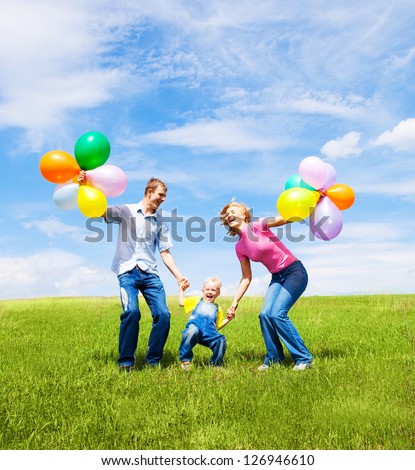 happy family with balloons  jumping outdoor on a warm summer day