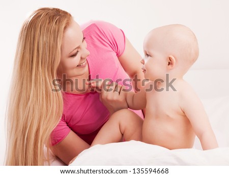 happy young mother and her one year old baby in bed at home