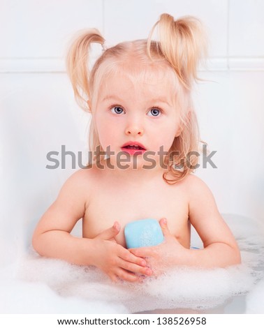 cute two year old girl taking a bath with foam and using soap