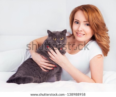 beautiful young woman with a cat in bed at home