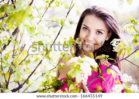 beautiful brunette woman in the park standing near the apple tree on a warm summer day