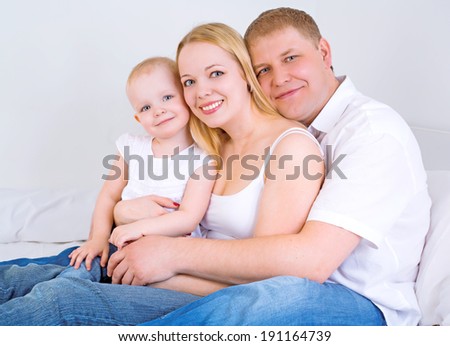 happy family: mother, father and baby in bed at home