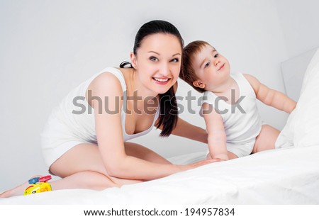happy young mother with her two year old baby in bed at home