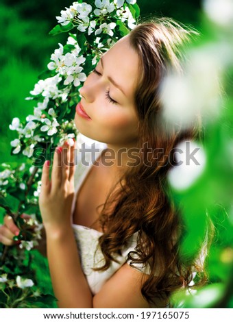 beautiful young woman in the summer park, standing near the apple tree with flowers