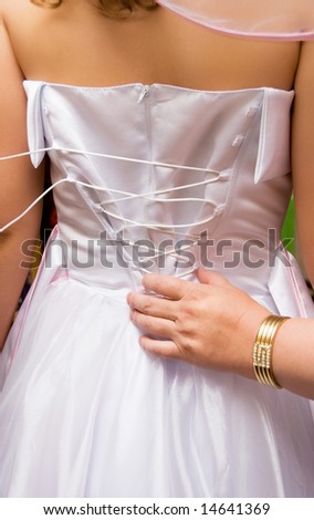 mother tightening a corset on her daughter\'s wedding dress