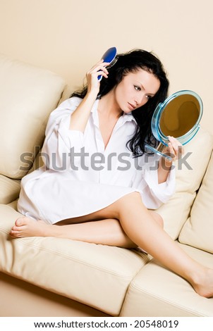 sexy beautiful brunette woman with a mirror brushing her hair
