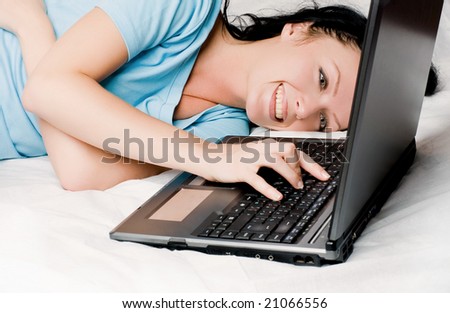 cheerful beautiful young brunette woman with a laptop on the bed