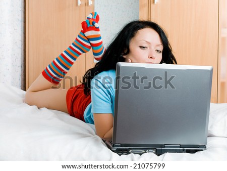 beautiful thoughtful brunette girl with a laptop on the bed