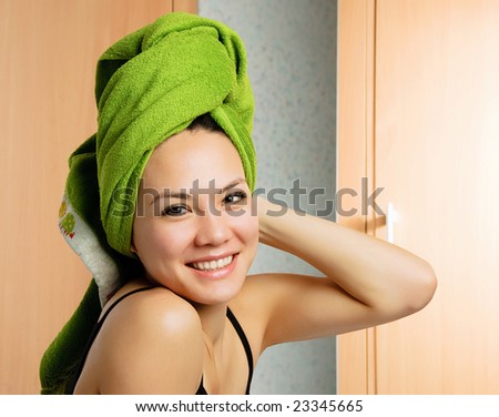 beautiful young cheerful woman in the bedroom with a towel on her head
