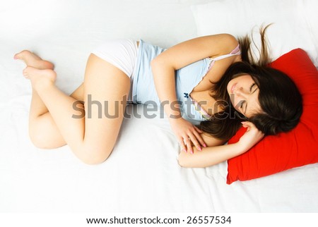 beautiful young brunette woman sleeping peacefully in her bed without a blanket