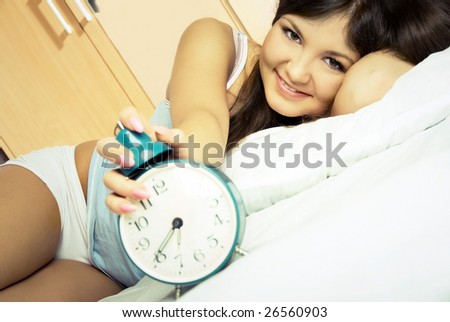happy beautiful young woman waking up and switching off the alarm clock
