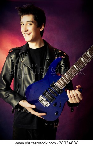 portrait of a handsome young man wearing a leather jacket with a guitar