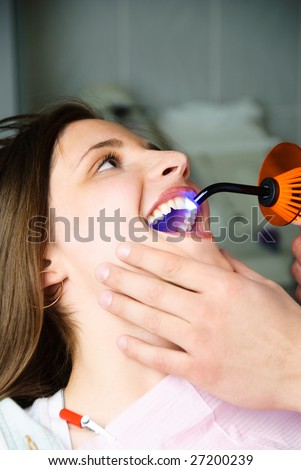 dentist curing the patient\'s teeth with ultraviolet lamp in his office