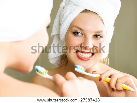 pretty girl at home looking into the mirror and brushing teeth