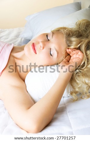 beautiful young blond woman sleeping peacefully in her bed at home