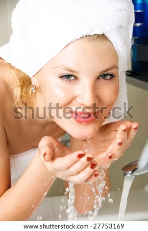 beautiful happy woman washing her face in the bathroom
