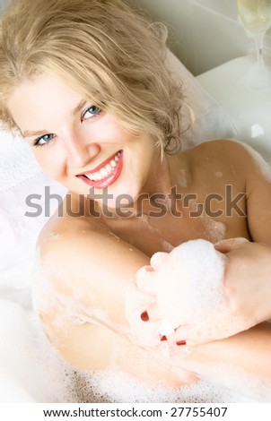 beautiful young blond woman relaxing in a bath with foam