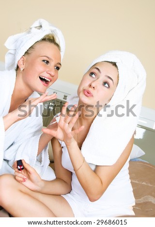 pretty young women at home applying nail polish and blowing on the nails