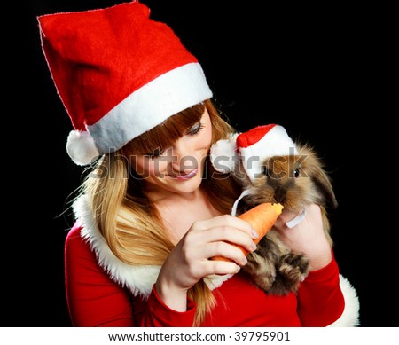 blond girl dressed as Santa feeding a rabbit with a carrot