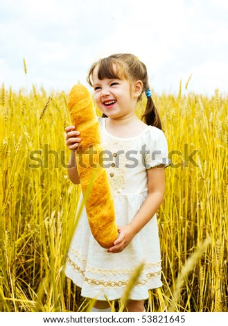 happy cute little girl in the wheat field with a long loaf