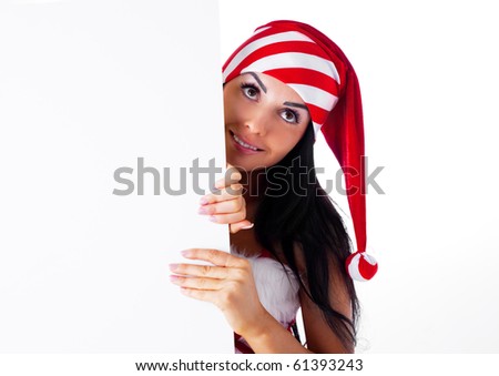 pretty young brunette woman wearing a Santa\'s hat hiding behind a blank sheet of paper