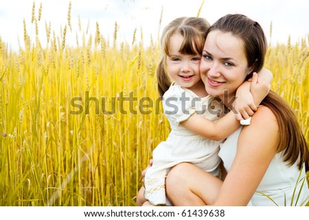 beautiful young mother and her daughter having fun at the wheat field