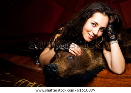 luxurious young brunette woman drinking vine on the bear skin rug