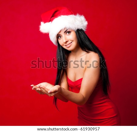 beautiful brunette girl wearing a Santa\'s hat and holding something in her hands, place your product here
