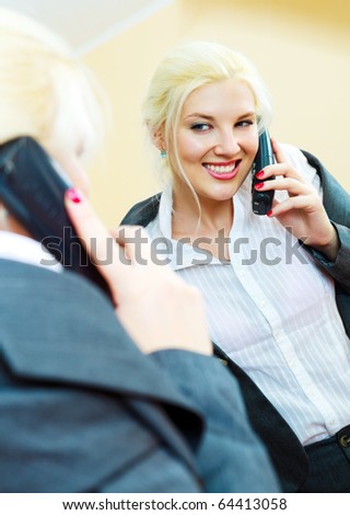 young confident businesswoman talking on the phone and looking at herself in the mirror