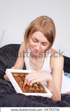 pretty young woman eating candies at home on the bed