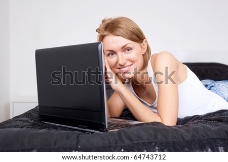 beautiful young woman with a laptop on the bed at home