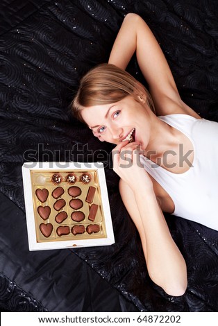 pretty young woman eating candies at home on the bed