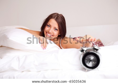 pretty happy girl waking up in the morning and switching off the alarm clock