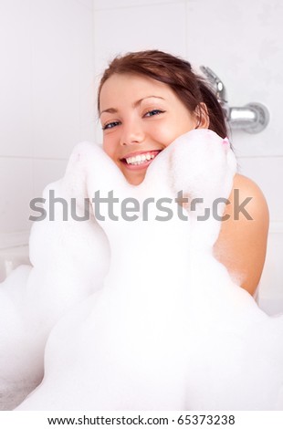 beautiful young brunette woman taking a relaxing bath with foam