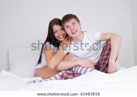 happy young couple sit on the bed at home