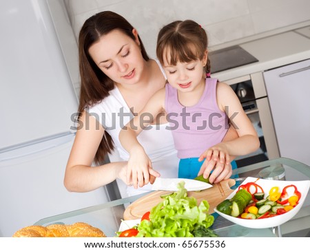 young mother and her five year old daughter cook together on the kitchen at home