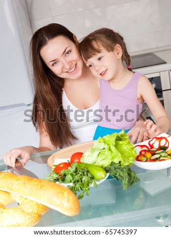 young mother and her five year old daughter cook together on the kitchen at home