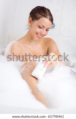beautiful young brunette woman taking a relaxing bath and deleting hair with electric epilator