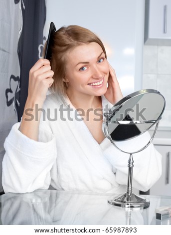 beautiful young woman looking into the mirror and brushing her hair
