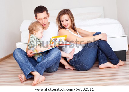 happy family, mother ,father and their baby read a book at home (focus on the father)
