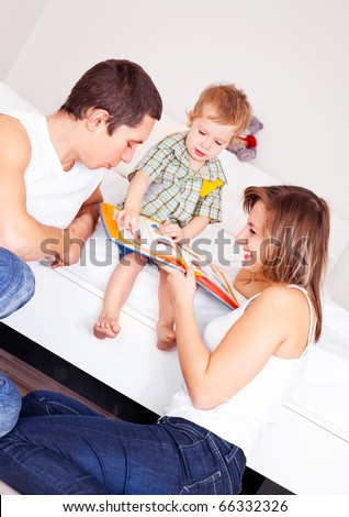 happy family, mother ,father and their baby read a book at home (focus on the mother and father)