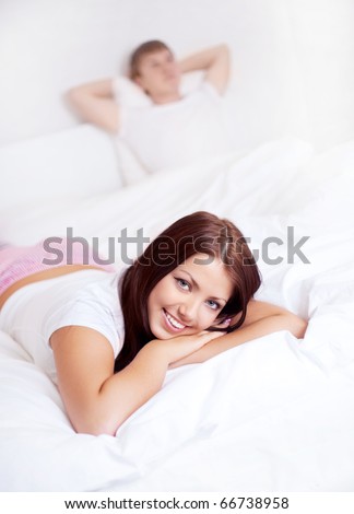happy young woman and  sleeping man on the bed at home (focus on the woman)