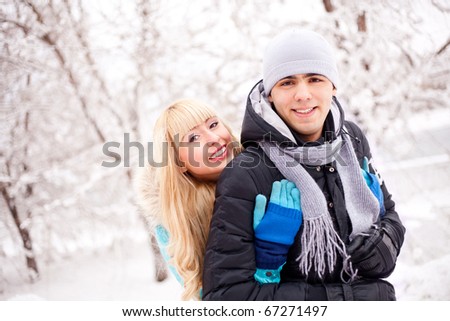 happy young beautiful couple having a walk in winter park (focus on the woman)