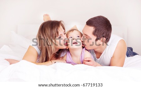 happy family, mother ,father and their baby on the bed at home (focus on the child)